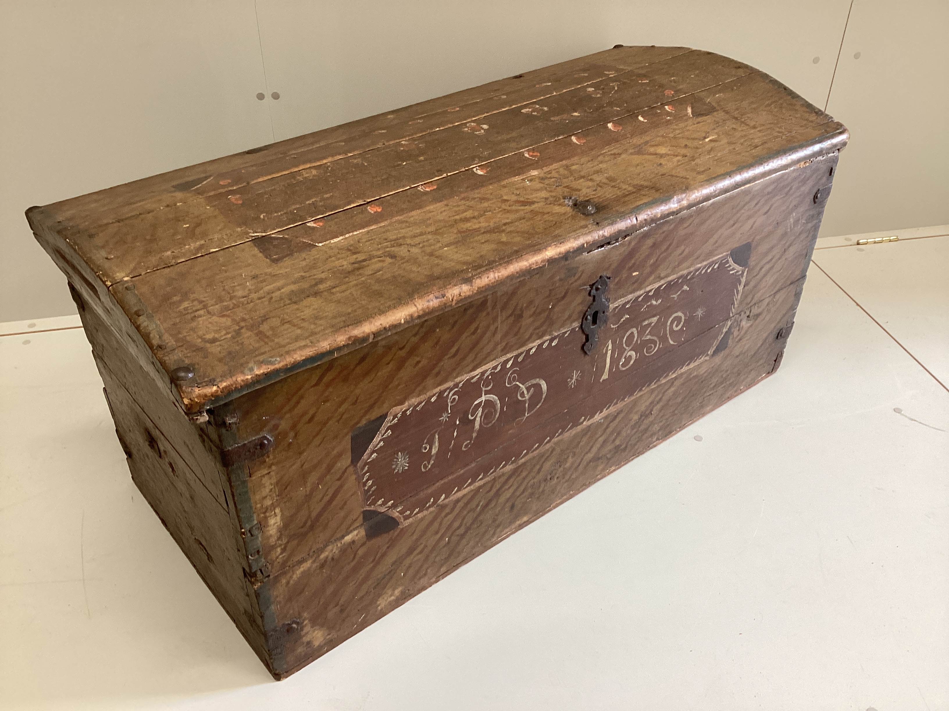 A 19th century pine domed top trunk with painted simulated grain initialled “I.P.D” and dated 1830, width 115cm, depth 53cm, height 56cm.